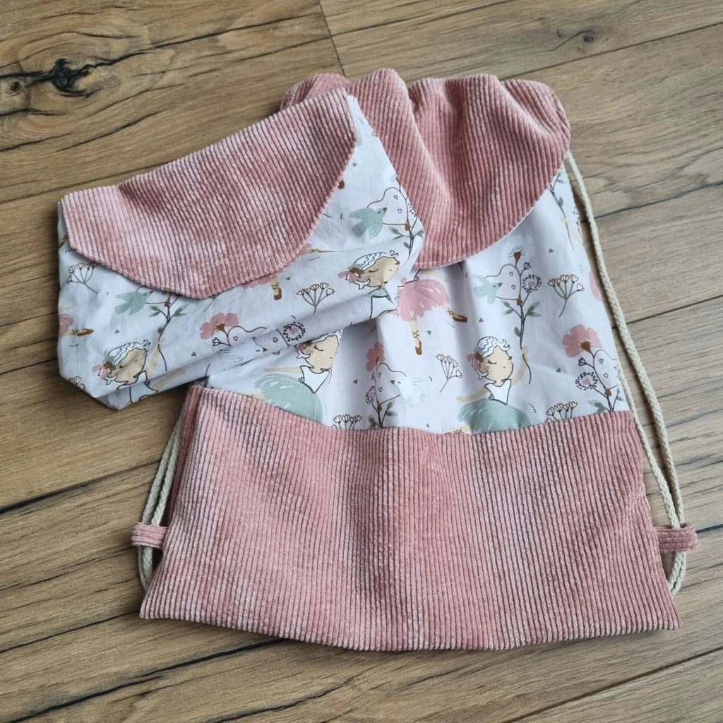 Ensemble assorti d'un sac à dos pochon et d'une pochette imperméable au motif danseuse. A droite, le sac à dos au format pochon cousu dans un tissu imprimé au motif danseuse avec une base en velours côtelé rose et un rabat arrondi également en velours côtelé rose. Ce sac se ferme grâce à deux cordelettes en coton blanc de part et d'autre du sac. A gauche, une petite pochette imperméable cousu dans le même tissu au motif danseuse et disposant d'un rabat en velours côtelé rose également.