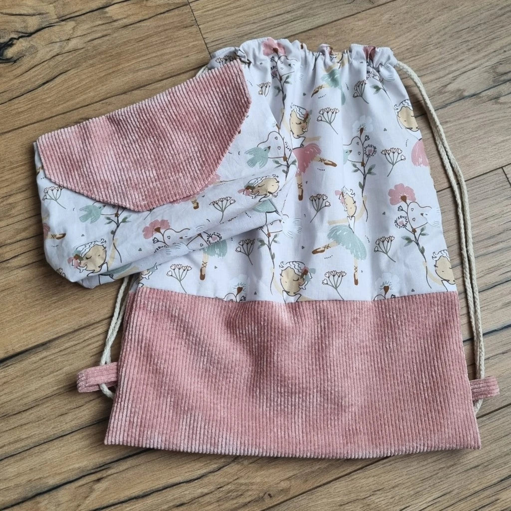 Ensemble assorti d'un sac à dos pochon et d'une pochette imperméable au motif danseuse. A droite, le sac à dos au format pochon cousu dans un tissu imprimé au motif danseuse avec une base en velours côtelé rose. Ce sac se ferme grâce à deux cordelettes en coton blanc de part et d'autre du sac. A gauche, une petite pochette imperméable cousu dans le même tissu au motif danseuse et disposant d'un rabat en velours côtelé rose également.