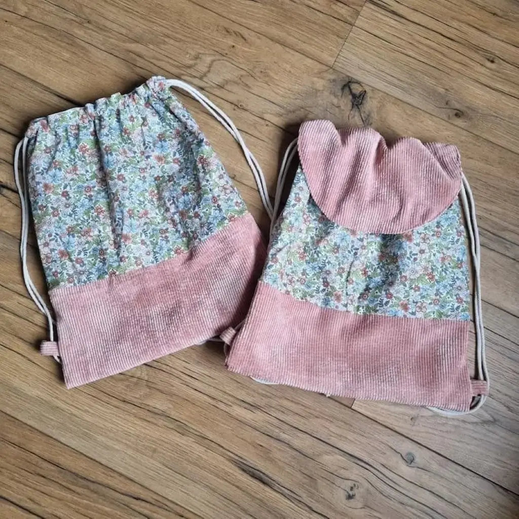 Ensemble assorti de deux sacs à dos pochons au motif fleurs. Celui de gauche a une base en velours côtelé rose mais ne dispose pas de rabat. Celui de droite est le même mais avec un rabat en velours côtelé rose également.