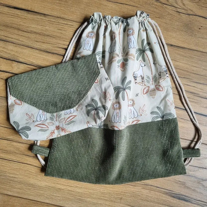 Ensemble fait main composé d’un sac à dos pochon sans rabat et d’une pochette assortie, en tissu imprimé jungle avec animaux exotiques et base en velours côtelé vert. Fermeture du sac par cordons coulissants. Idéal pour enfant, maternelle ou cadeau personnalisé.