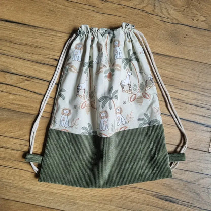 Sac à dos pochon pour enfant en tissu imprimé jungle avec animaux exotiques et base en velours côtelé vert. Modèle sans rabat, avec fermeture par cordons coulissants. Idéal pour la maternelle, la crèche ou comme sac de rangement léger fait main.
