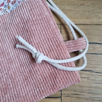 Zoom sur la base en velours côtelé rose et sur la cordelette en coton blanc du sac à dos format pochon motif liberty pour enfant.