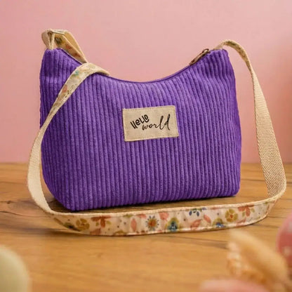Sac à main violet lavande en velours côtelé, étiquette Hello World et sangle fleurie.