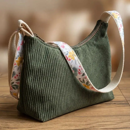 Sac bandoulière velours côtelé vert sapin avec large sangle en toile fleurie printanière.