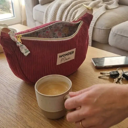 sac demi-lune lie de vin en velours côtelé posé sur table basse avec clés et téléphone