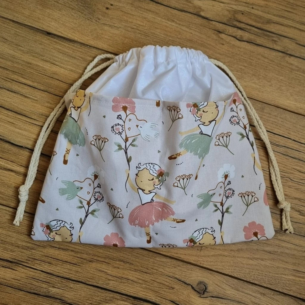 Sac piscine imperméable au format pochon se fermant grâce à deux cordelettes en coton blanc de part et d'autre et cousu avec un tissu imprimé à motif danseuse.