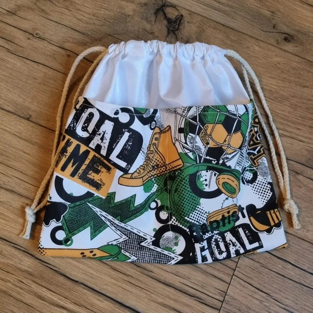 Sac piscine imperméable au format pochon se fermant grâce à deux cordelettes en coton blanc de part et d'autre et cousu avec un tissu imprimé à motif football avec une dominante de vert..