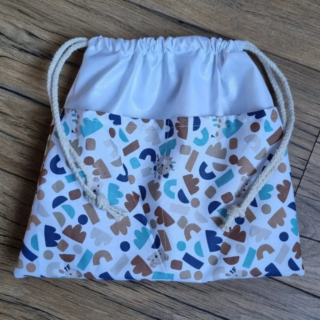 Sac piscine imperméable au format pochon se fermant grâce à deux cordelettes en coton blanc de part et d'autre et cousu avec un tissu imprimé à motif ptiwi.