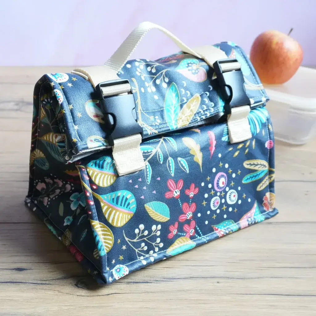 Petit sac lunch bag isotherme nuit fleurie en coton enduit avec poignée beige et clips noir sur bois