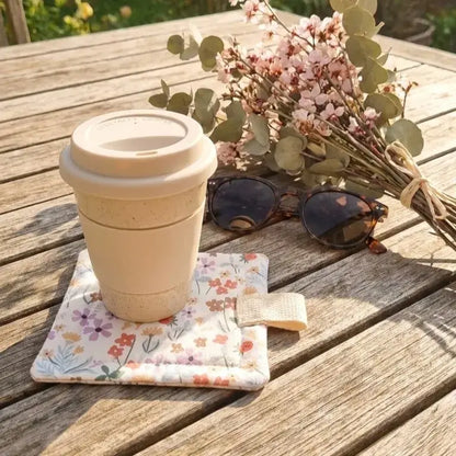 sous-verre molletonné en tissu fleuri avec gobelet réutilisable sur table extérieure