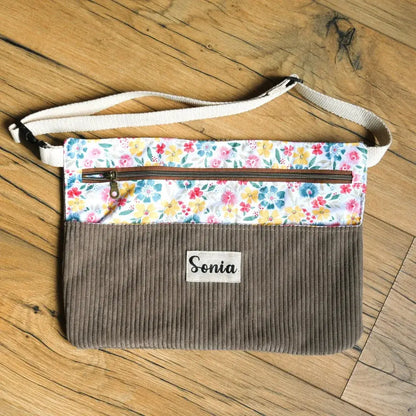 Tablier créatif personnalisé en velours côtelé taupe et tissu fleuri multicolore, idéal pour la couture, le DIY et les activités manuelles. Doté d’une poche zippée pratique pour garder les accessoires à portée de main et d’une ceinture ajustable en sangle écrue, ce tablier artisanal associe confort et style. La personnalisation avec prénom en fait un modèle unique et tendance pour adultes ou enfants.