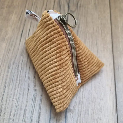 Trousse berlingot en tissu velours côtelé jaune posée sur un parquet en chêne