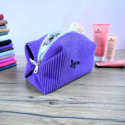 Trousse carrée personnalisée en velours côtelé lavande, ornée du prénom “Léa” floqué sur le devant. Son tissu doux et sa fermeture éclair claire offrent un style élégant et pratique. Doublée d’un coton à motifs fleuris, cette trousse artisanale permet de ranger maquillage, accessoires ou produits de soin avec raffinement. Idéale comme cadeau unique et sur mesure.