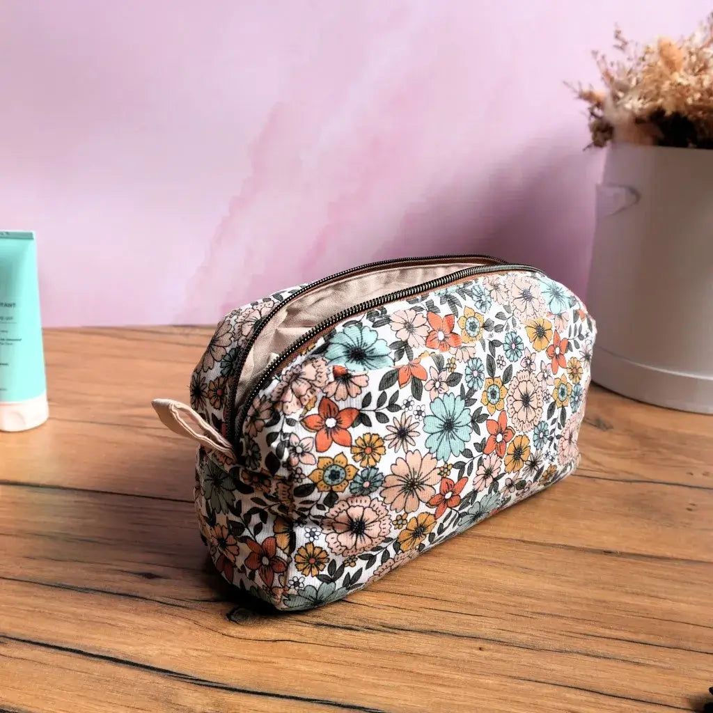 Trousse de toilette en tissu fleuri aux tons pastel, avec doublure beige et fermeture éclair robuste. Élégante et pratique, elle offre un rangement idéal pour maquillage, produits de soin ou accessoires de voyage. Son design rétro et ses finitions soignées en font un accessoire artisanal incontournable pour allier style, organisation et praticité au quotidien.