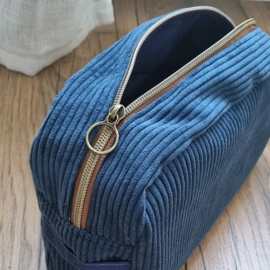 Trousse de toilette en velours côtelé bleu foncé avec son zip ouvert laissant apparaître un tissu intérieur uni bleu foncé.