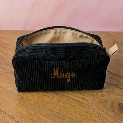 Trousse de toilette velours côtelé noire personnalisée Hugo, texte doré, doublure unie beige.