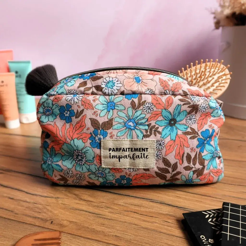 Trousse de toilette en tissu coloré à fleurs tropicales bleu et corail, avec étiquette « Parfaitement imparfaite ». Pratique et tendance, cette trousse zippée est idéale pour ranger maquillage, accessoires ou produits de soin. Son design fleuri apporte une touche originale et vitaminée à vos produits de beauté, que ce soit en voyage ou au quotidien.