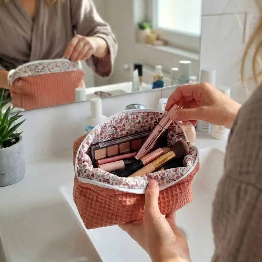 trousse maquillage nid d’abeille marsala ouverte avec produits beauté devant miroir