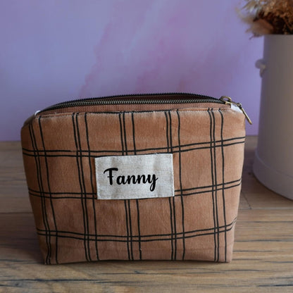 Trousse zippée personnalisée en velours marron à motif carreaux noirs, ornée d’une étiquette en tissu avec le prénom Fanny floqué en noir. Accessoire fait main idéal comme trousse de toilette, trousse à maquillage ou pochette de rangement. Son design sobre et élégant, associé à la personnalisation, en fait un cadeau pratique et unique pour adulte ou enfant.
