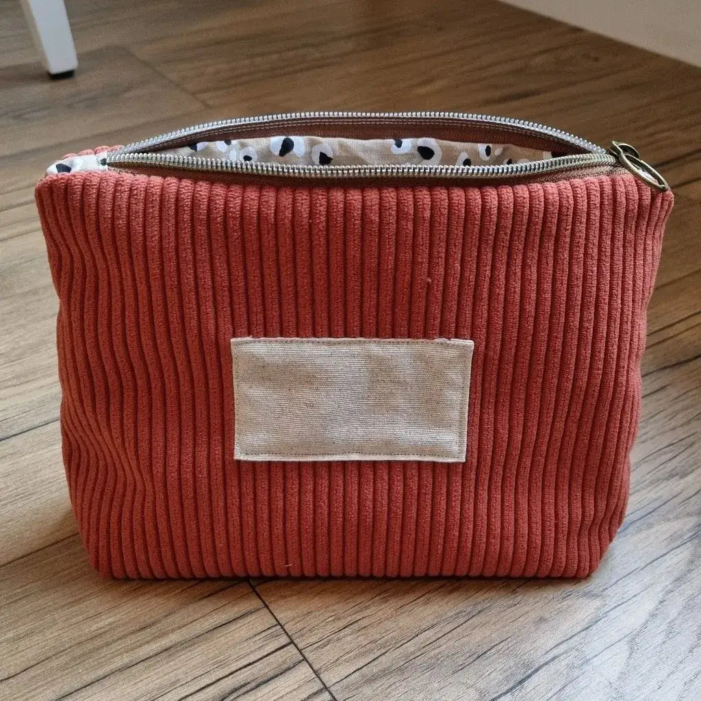 Trousse zippée en velours côtelé terracotta doublée avec un tissu en coton imprimé à motif léopard. Cette trousse dispose d'une étiquette en tissu cousue en façade pouvant accueillir un prénom ou une inscription personnalisée qui sera floquée dessus.