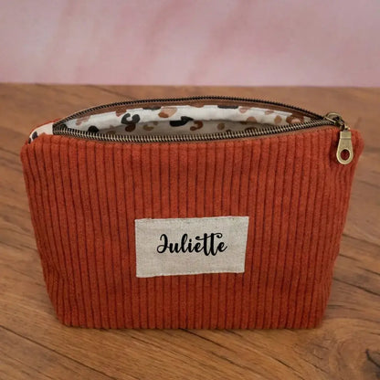 Trousse zippée en velours côtelé terracotta doublée avec un tissu en coton imprimé à motif léopard. Cette trousse dispose d'une étiquette en tissu cousue en façade pouvant accueillir un prénom ou une inscription personnalisée qui sera floquée dessus.