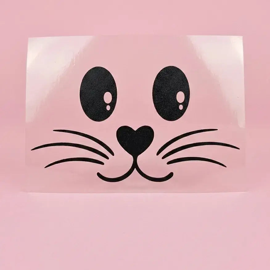 Flex thermocollant noir : visage de lapin avec yeux ovales, nez en cœur et moustaches, sur support transparent et fond rose.