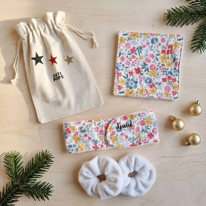 Coffret à fleurs multicolores vu du dessus : pochon à étoiles, lingette lavable, bandeau prénom Louise et chouchous éponge