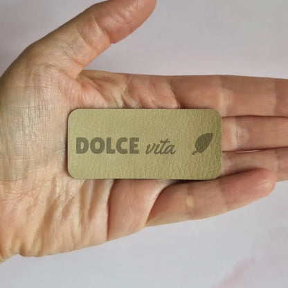 Étiquette simili cuir gravée Dolce vita avec petite feuille, texture grainée visible