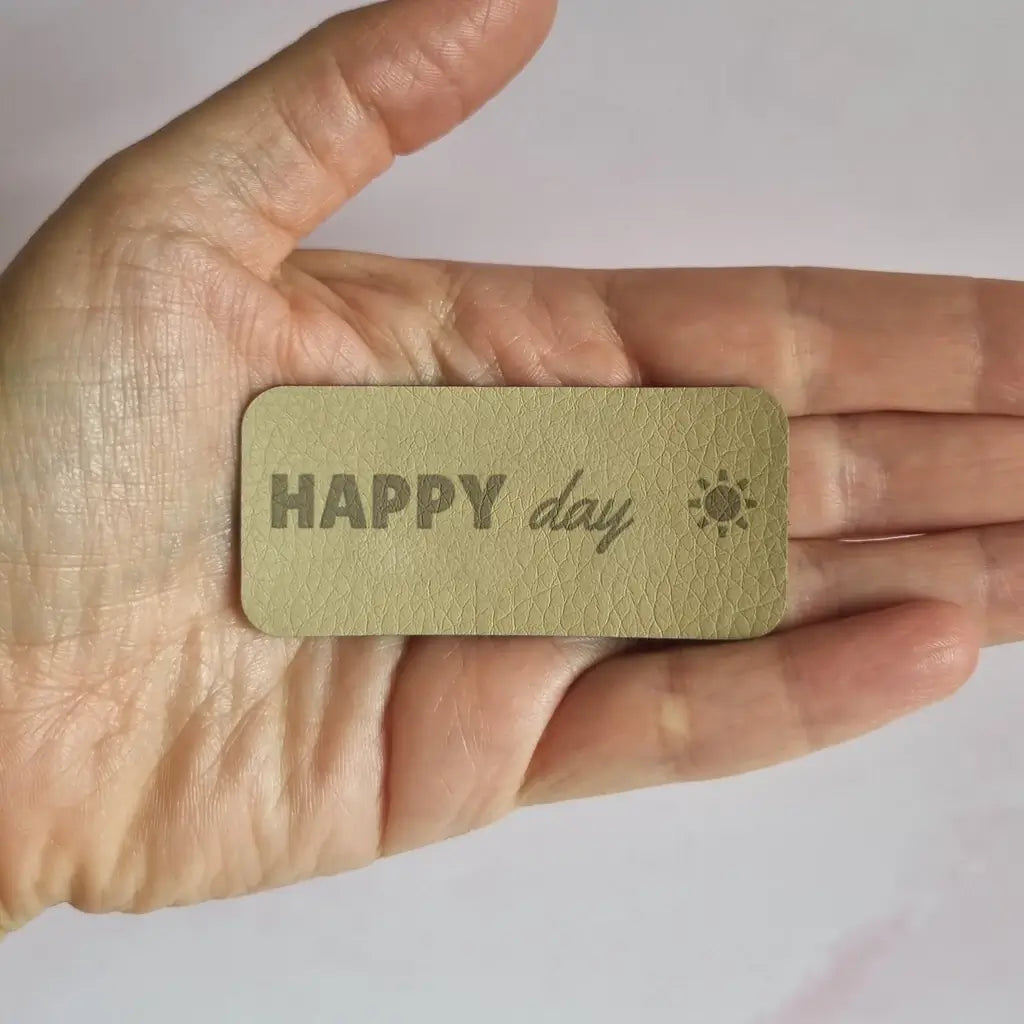 Étiquette simili cuir gravée Happy day sur une seule ligne avec petit soleil