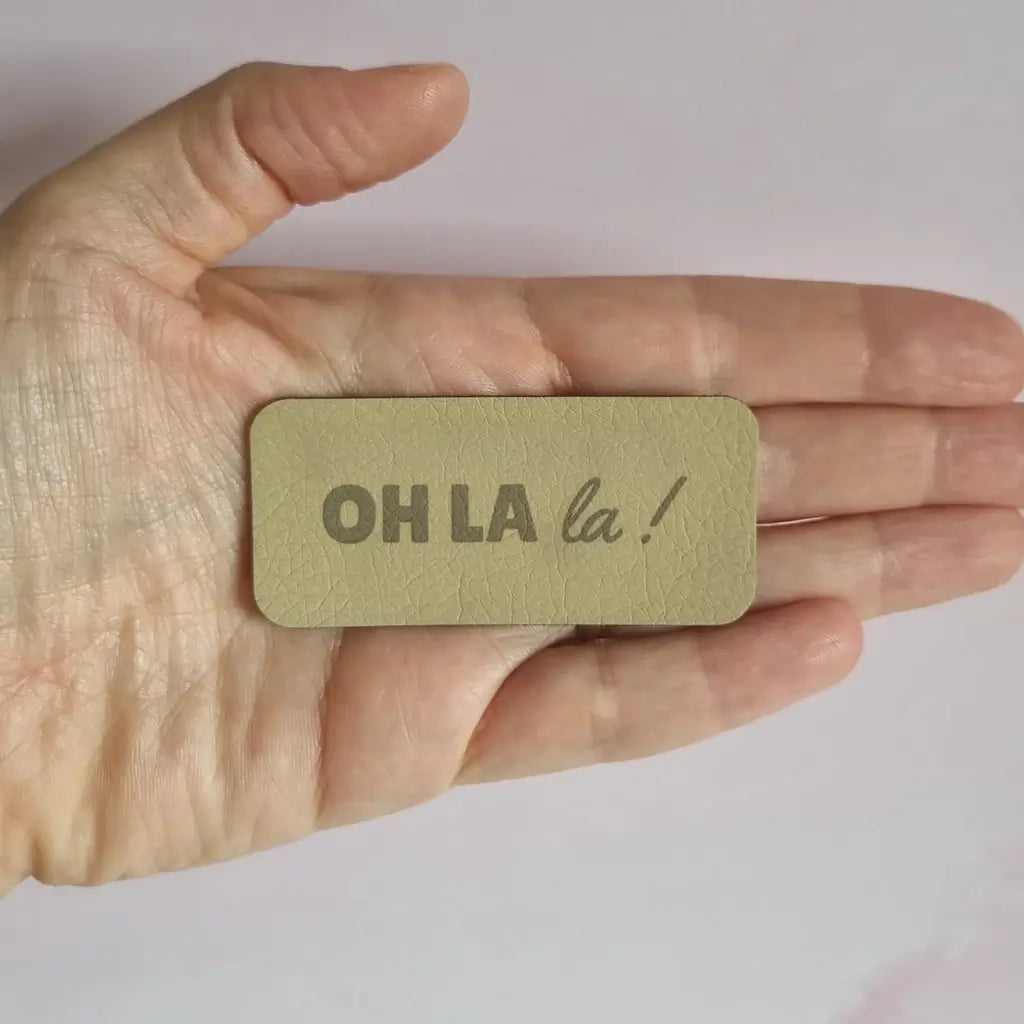 Étiquette rectangulaire en simili cuir gravée Oh la la, posée dans la paume