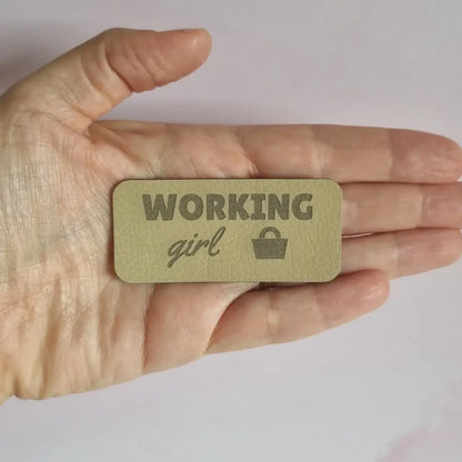Étiquette simili cuir gravée Working girl avec petit sac à main, vue dans la main