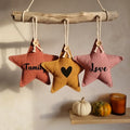 Trois étoiles décoratives en tissu rose, ocre et vieux rose suspendues à une branche, inscriptions Family, cœur et Love