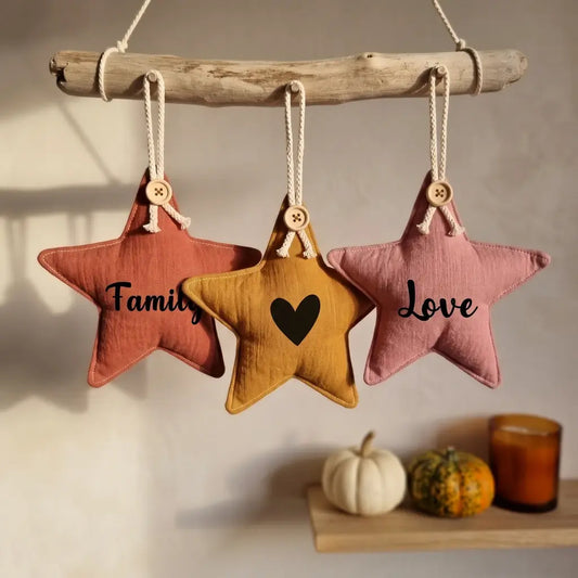 Trois étoiles décoratives en tissu rose, ocre et vieux rose suspendues à une branche, inscriptions Family, cœur et Love