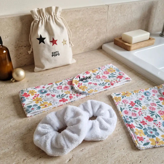 Kit soin visage fleurs multicolores : bandeau prénom Louise, lingette lavable et chouchous éponge sur un plan de vasque