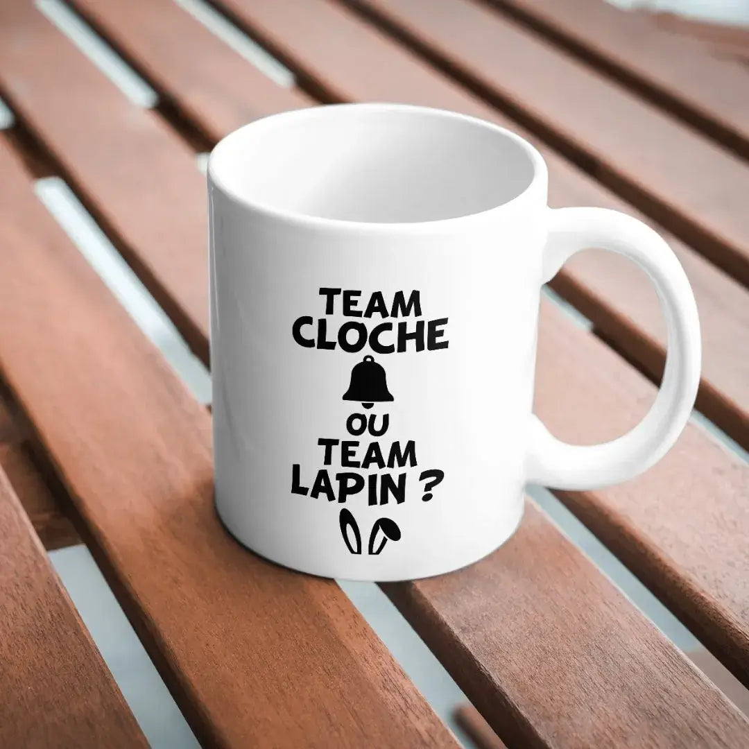 mug blanc avec texte Pâques team cloche ou team lapin imprimé en noir sur table bois