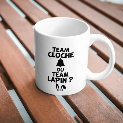 mug blanc avec texte Pâques team cloche ou team lapin imprimé en noir sur table bois