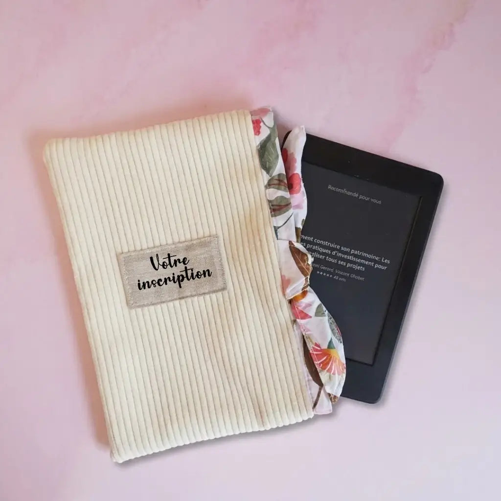 Pochette liseuse en velours côtelé écru à doublure fleurie, étiquette à personnaliser et liseuse dépassant