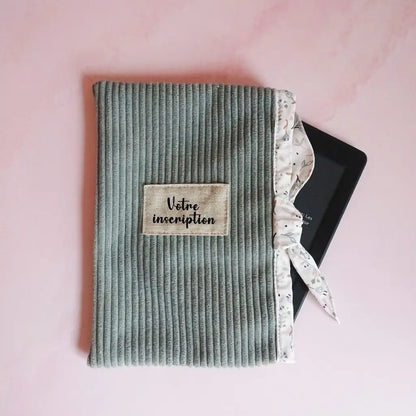Pochette liseuse vert sauge en velours côtelé, lien fleuri noué et étiquette à personnaliser sur le devant