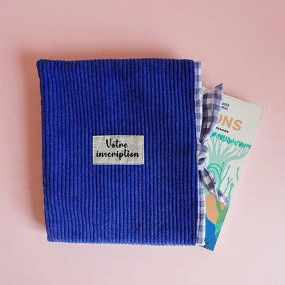 Pochette à livre en velours côtelé bleu roi avec doublure vichy, livre dépassant sur le côté
