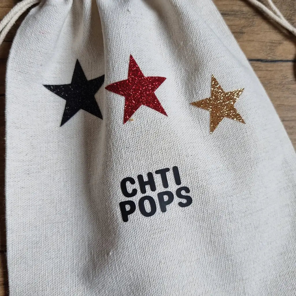 gros plan sur le pochon en coton écru avec trois étoiles pailletées (noire, rouge, dorée)
