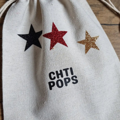 gros plan sur le pochon en coton écru avec trois étoiles pailletées (noire, rouge, dorée)