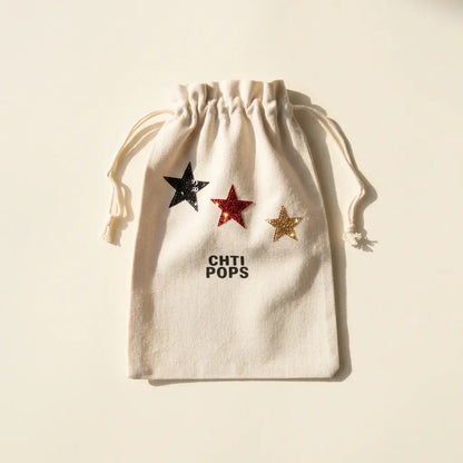 Pochon en toile écrue à cordons de serrage, orné de trois étoiles pailletées noire, rouge et dorée, vu de face