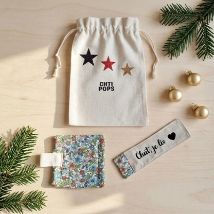 Pochon écru à étoiles, dessous de tasse fleuri à passant et marque-page « Chut, je lis » vus du dessus avec du sapin