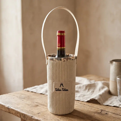 Porte-bouteille en velours côtelé écru Tchin Tchin avec bouteille de vin rouge et doublure fleurie, sur table en bois brut