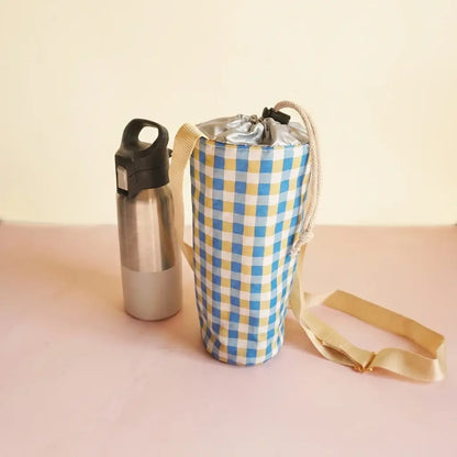 Porte-gourde à carreaux vichy bleus et jaunes, bandoulière écrue et fermeture par cordon