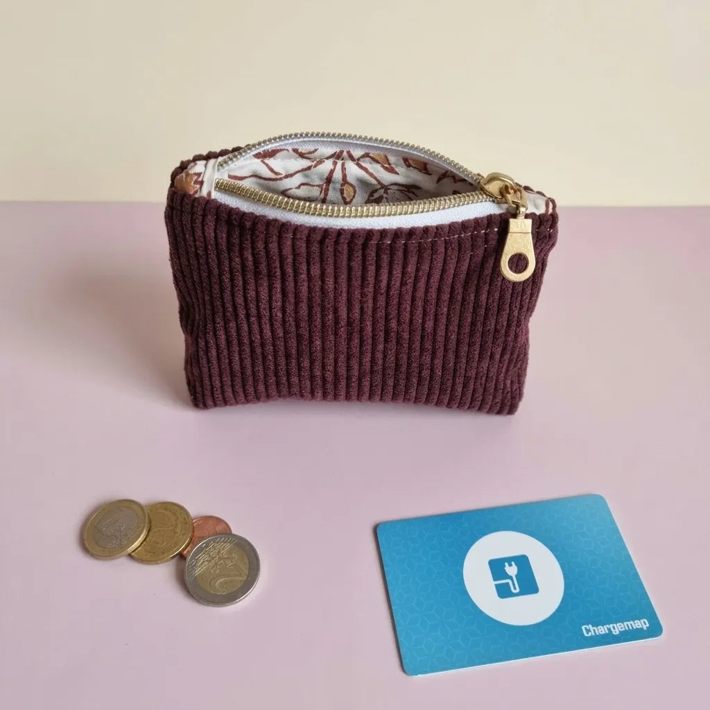 Porte-monnaie en velours côtelé prune à zip doré, entrouvert sur une doublure à feuillages