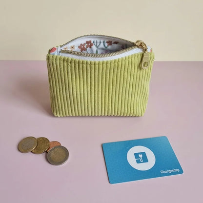 Porte-monnaie zippé vert anis en velours côtelé, doublure fleurie visible, posé près de pièces et d'une carte