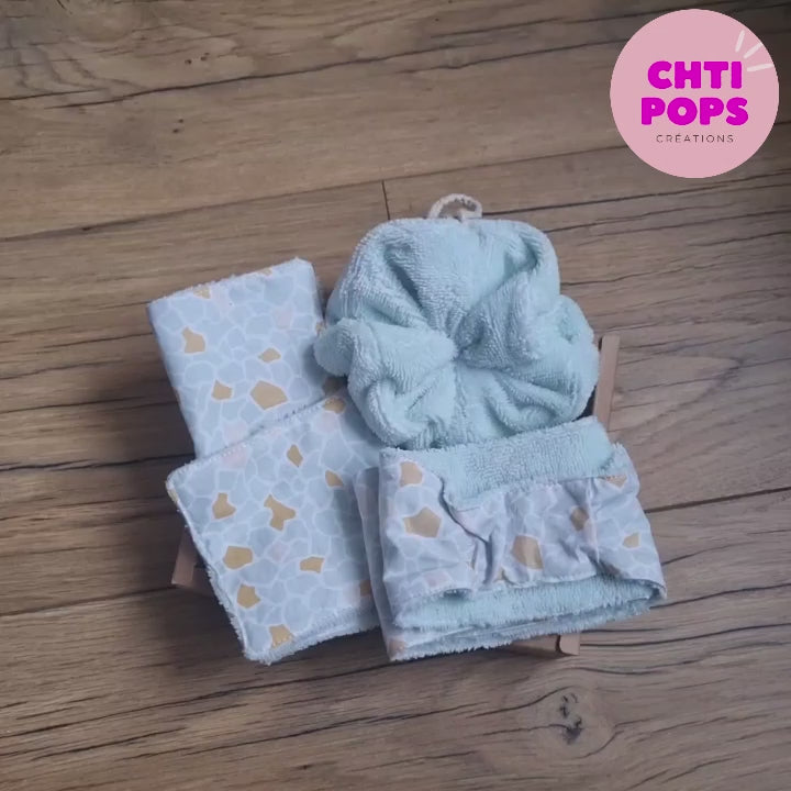 Vidéo présentant le coffret bien-être cocooning. Ce coffret comprend une lingette classique et une maxi-lingette avec une face en éponge de bambou de couleur céladon et une face en tissu coton imprimé au motif argeo, un bandeau de soin dans la même composition et une fleur de douche également en éponge de bambou.