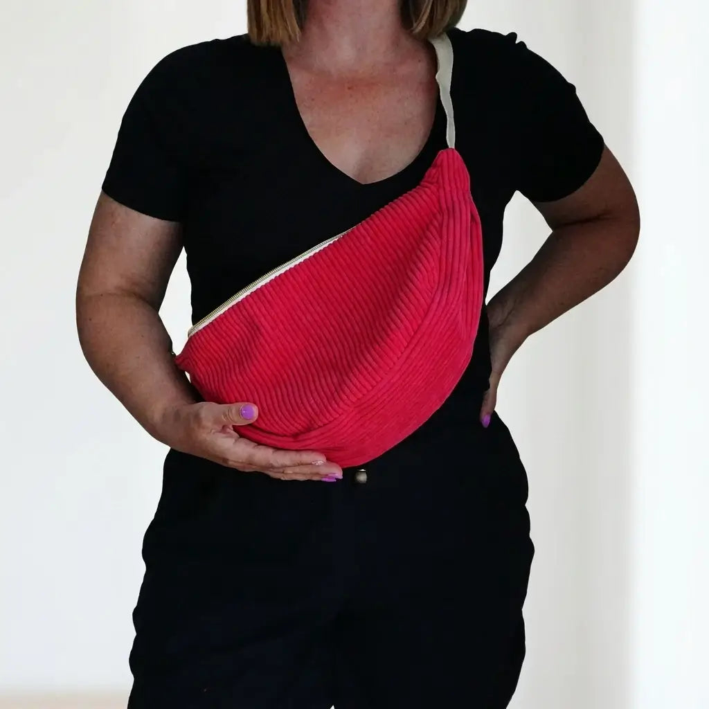 Sac banane rouge framboise en velours côtelé de forme demi-lune, porté en bandoulière