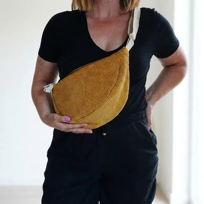 Sac banane jaune moutarde en velours côtelé porté en travers, sangle écrue sur l'épaule